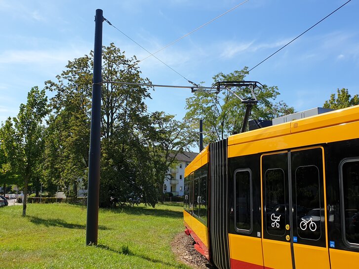 Die Stadtbahn fährt gerade an einem GFK Mast vorbei. 