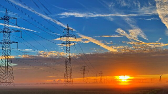Freileitungsinfrastuktur Freileitungsmaste bei Sonnenaufgang - für eine sichere und zuverlässige Energieversorgung