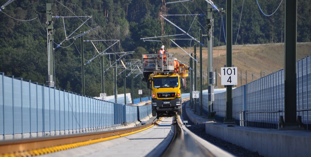 Monteure in Sicherheitskleidung führen Arbeiten an der Oberleitung durch.