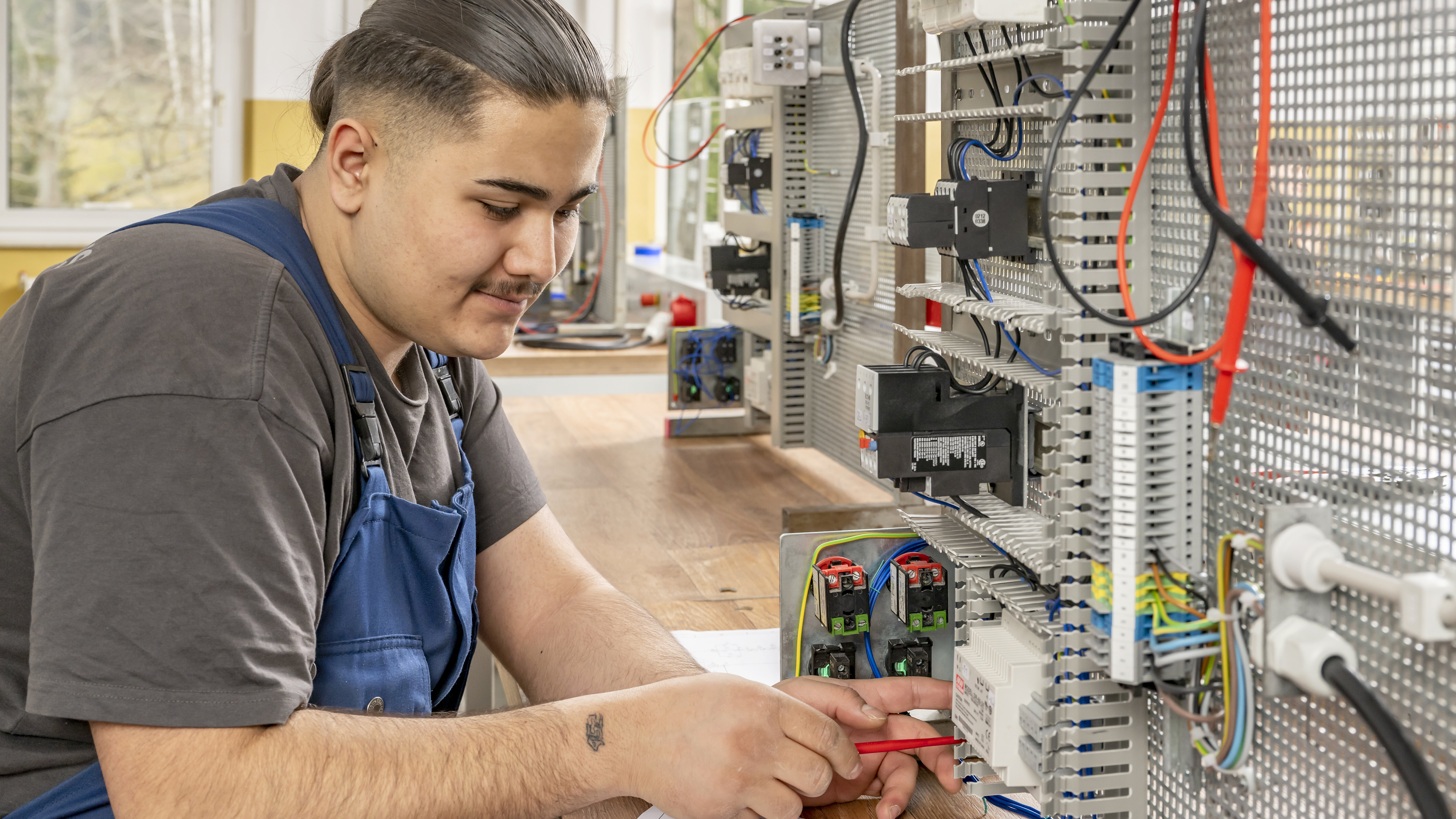 Ein auszubildender Industrieelektriker arbeitet an elektrischen Systemen.