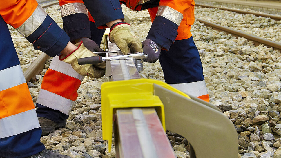 Zwei Monteure arbeiten an der dritten Schiene im Nahverkehr/U-Bahn